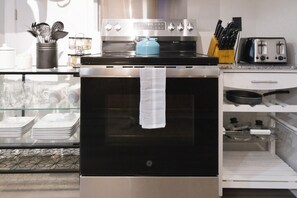 Una cocina con horno de acero inoxidable, hervidor azul y tostadora.