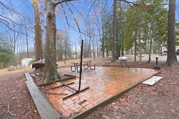 A picnic area with a brick patio, picnic tables, and a barbecue grill.