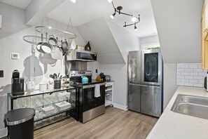 Una cocina moderna con un refrigerador de acero inoxidable, un microondas y una tetera.