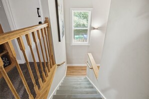 A staircase with wooden railings and a window with blinds. - The Divine Cottage: Woodsy Hideaway! (Richmond)