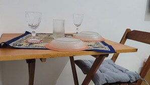 Una mesa de madera con un mantel individual, dos vasos transparentes y un recipiente de vidrio.