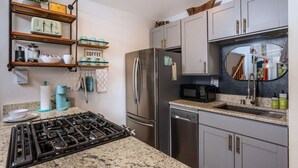 Cocina con estufa a gas, refrigerador de acero inoxidable y microondas.