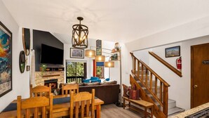 Una cocina moderna con comedor, muebles de madera, chimenea y escalera.