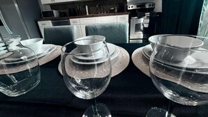 A modern kitchen with white cabinets, a microwave, oven, and a dining area with a table set for four with clear glassware and plates.