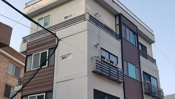 Un edificio de varios pisos con balcones, ventanas amplias y una entrada a nivel de calle con puertas de vidrio.