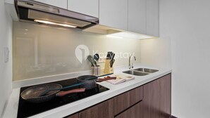 Una cocina moderna con estufa empotrada, pileta de acero inoxidable y alacenas de madera.