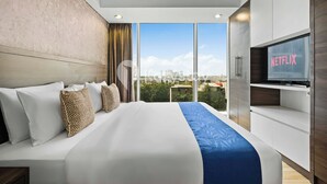 Una habitación de hotel moderna con una cama grande, televisión y vistas a la ciudad.