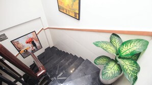 A staircase with a handrail, a framed picture of a bridge, and a potted plant. - De Lustora Hotel & Apartment - District 1, HCM. (Ho Chi Minh City)