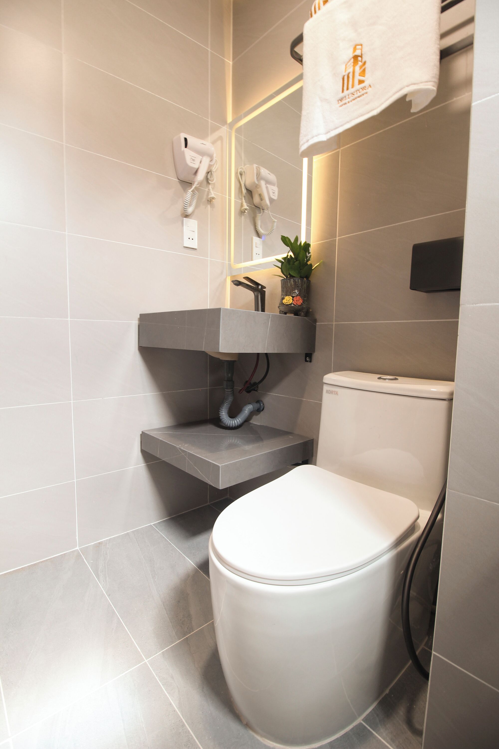 A modern bathroom with a toilet, a sink with a towel rack, and a wall-mounted phone.