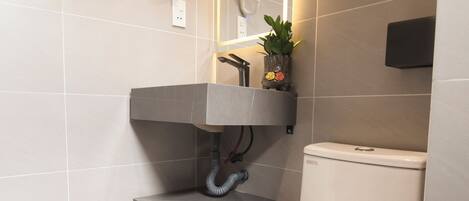 A modern bathroom with a toilet, a sink with a towel rack, and a wall-mounted phone.