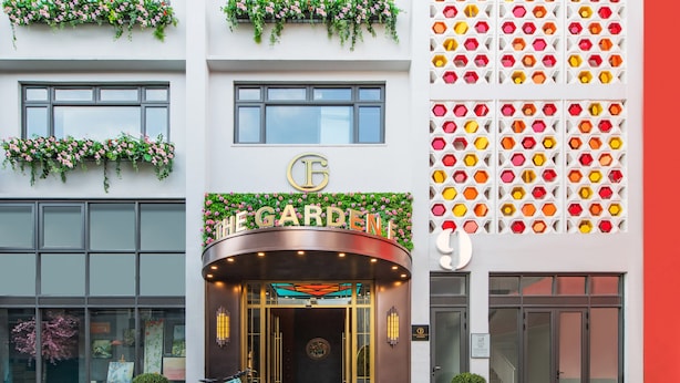 A hotel entrance with a curved facade, a sign reading "THE GARDEN", and a bike parked outside. - The Garden F (Shanghai)