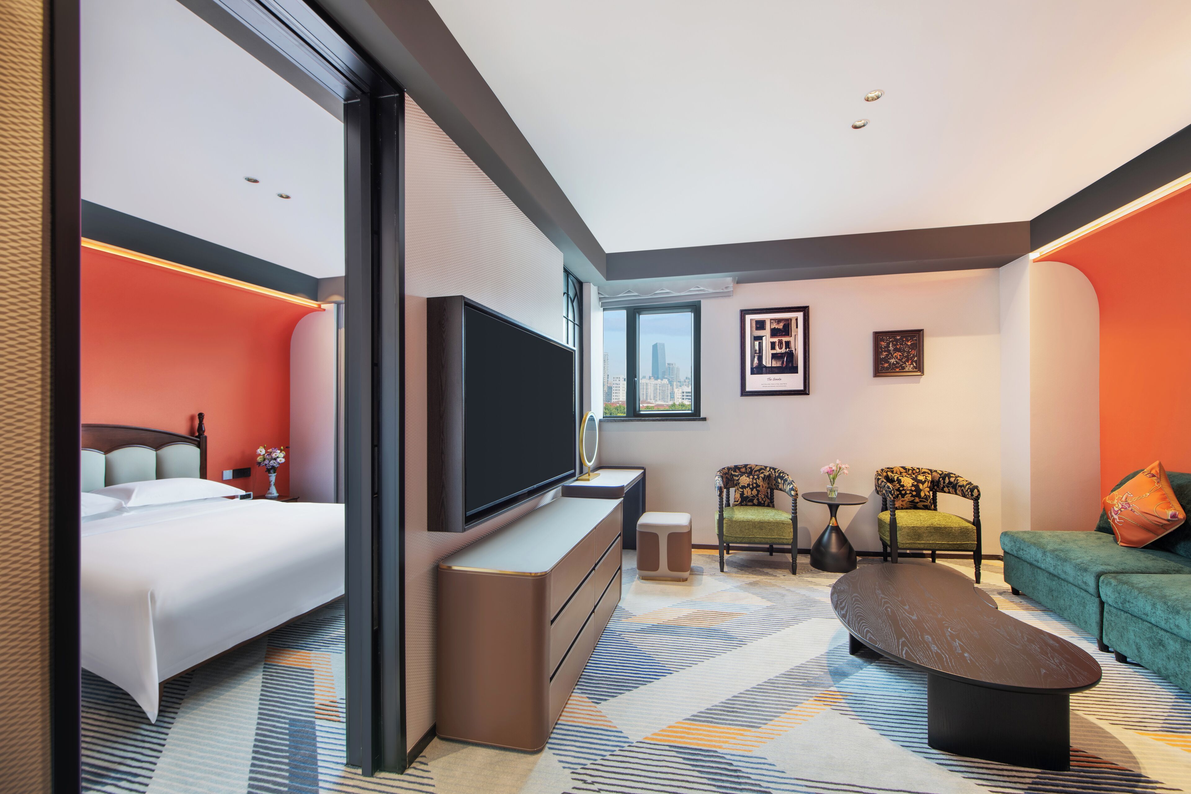 A modern hotel room with a bed, a TV, a sofa, and a coffee table.
