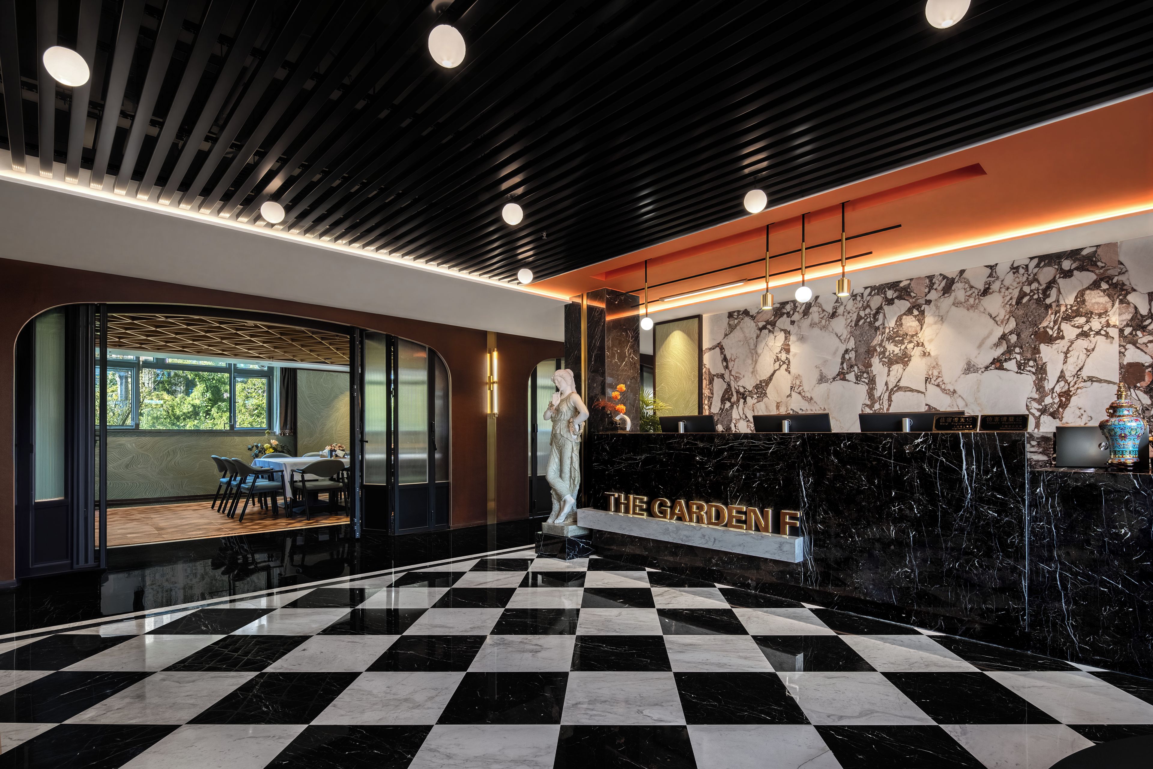 A hotel lobby with a checkered floor, a reception desk with a marble counter, and a statue.