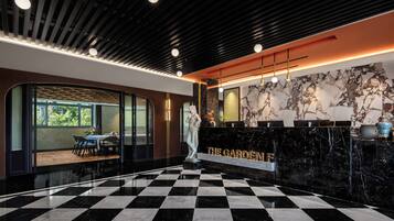 A hotel lobby with a checkered floor, a reception desk with a marble counter, and a statue.