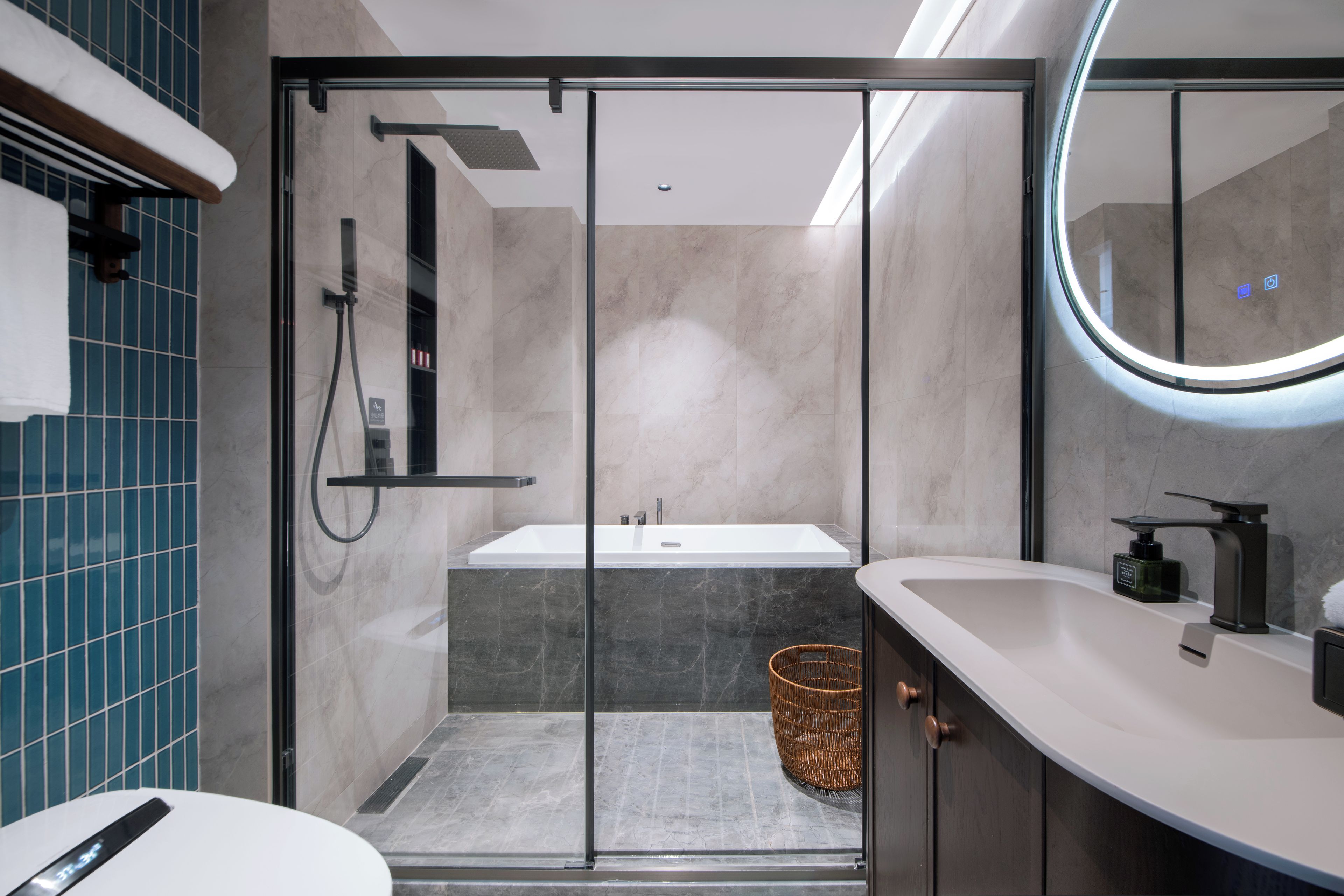 Un baño moderno con ducha envuelta en vidrio, una bañera independiente y un tocador con espejo.