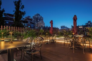 An outdoor dining area with tables and chairs, surrounded by a wooden fence and greenery. - The Garden F (Shanghai)