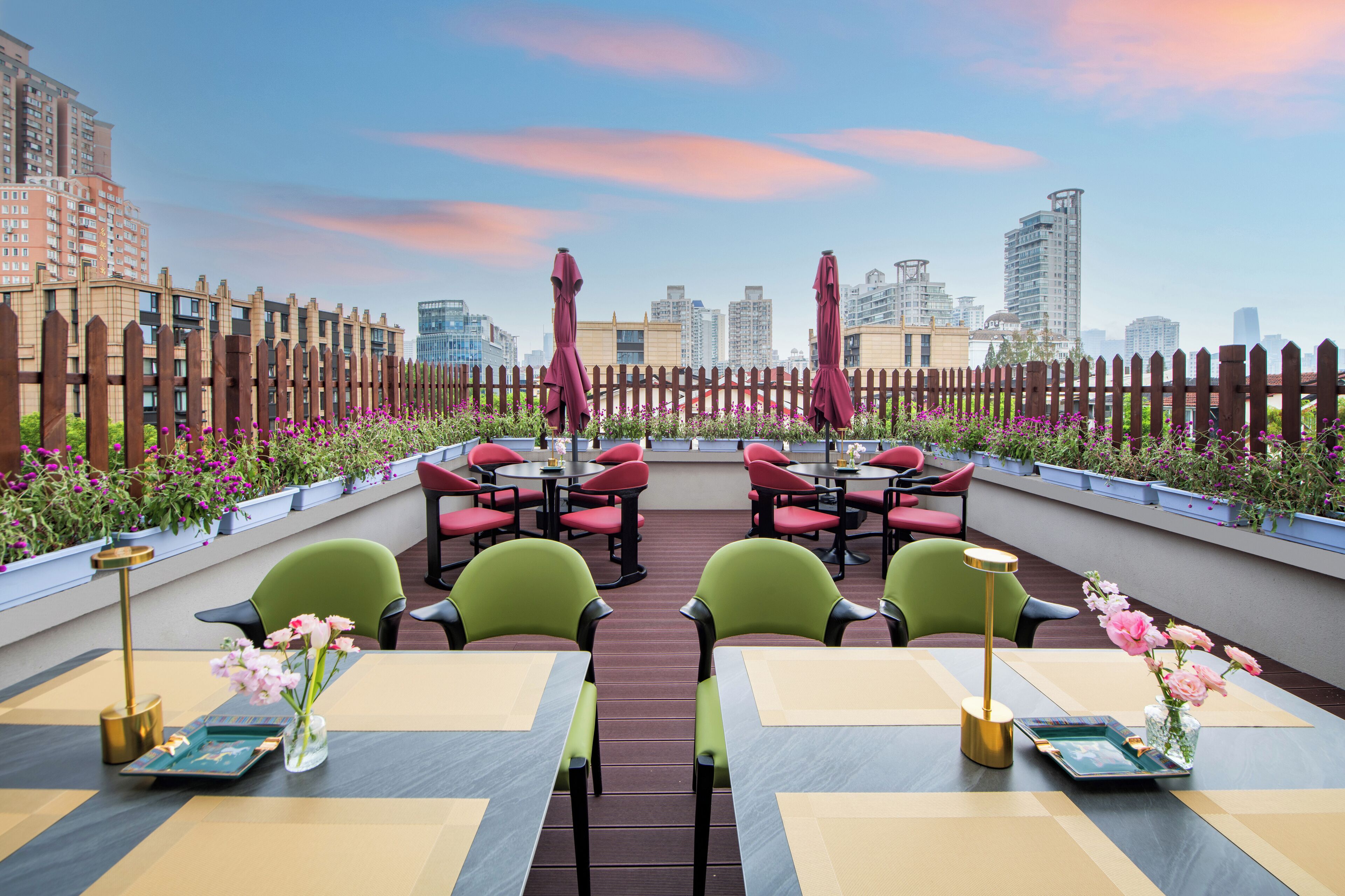 An outdoor seating area with tables and chairs, surrounded by a wooden fence and potted plants.