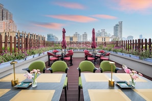 An outdoor seating area with tables and chairs, surrounded by a wooden fence and potted plants.