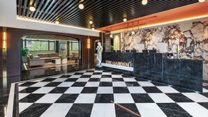 A lobby with a checkered floor, a reception desk, and a seating area with sofas. - The Garden F (Shanghai)