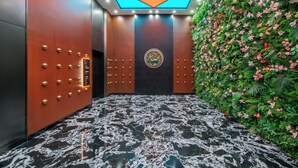 Ein Aufzug mit Marmorboden, dekorativer Decke und einer Wand mit künstlichen Pflanzen und Blumen.