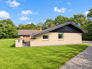 A single-story house with a sloped roof, a small porch, and a well-maintained lawn. - 12 Person Holiday Home in Oksbol (Oksbol)