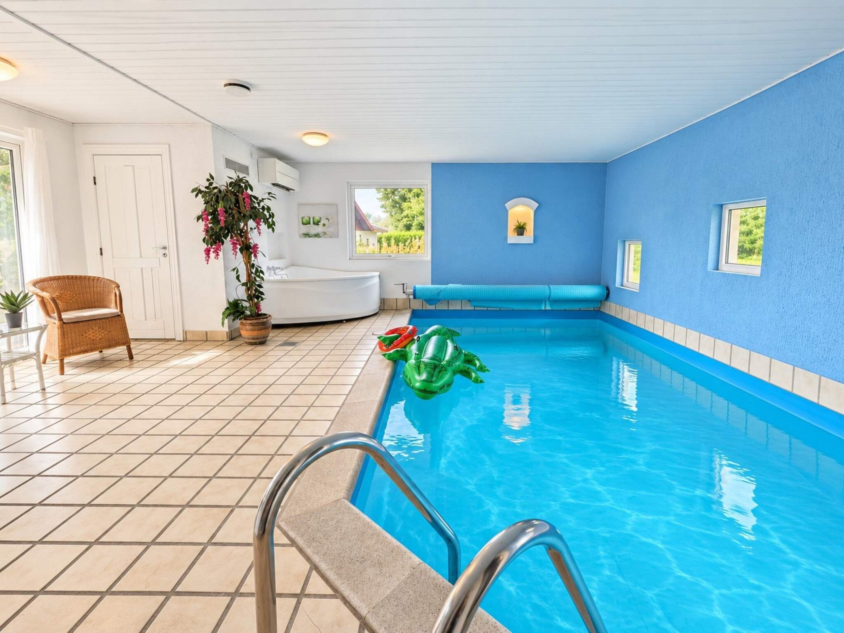 A swimming pool with a blue interior, a white door, a wicker chair, and a potted plant.
