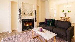 Una sala de estar con chimenea, un sofá, una mesa de centro y un comedor.