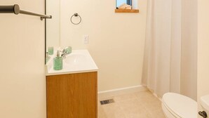 Un baño con inodoro, lavamanos, espejo y cortina de ducha.