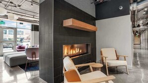 A modern lounge area with a fireplace, comfortable seating, and a view of the city.