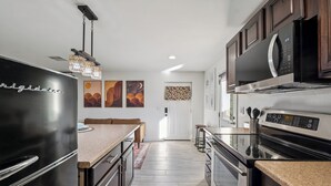 Una cucina moderna con elettrodomestici in acciaio inossidabile, un piano di lavoro in legno e un'area pranzo con una panca.