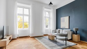 Una sala de estar moderna con un sofá, una mesa de centro y un televisor sobre un mueble.