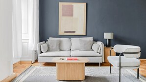 Una sala de estar moderna con un sofá gris, una mesa de centro de madera y un sillón gris.