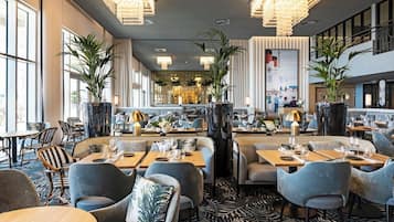 Un restaurante moderno con techos altos, candelabros y una zona de bar central.