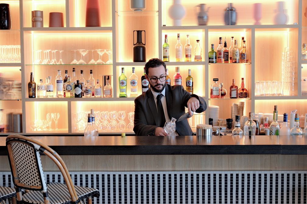 Zona de bar con estantes llenos de botellas de licores y vasos.