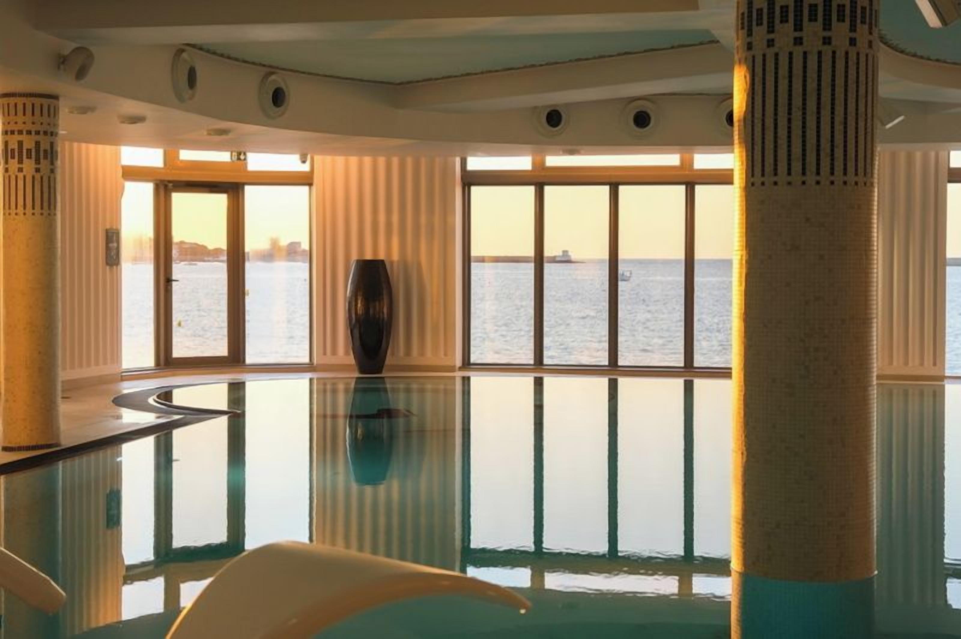 A spacious indoor area with a glass floor, large windows, and a view of the water.