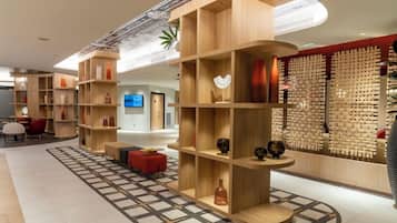 A modern hotel lobby with wooden shelving units, a patterned floor, and a wall of woven textiles.