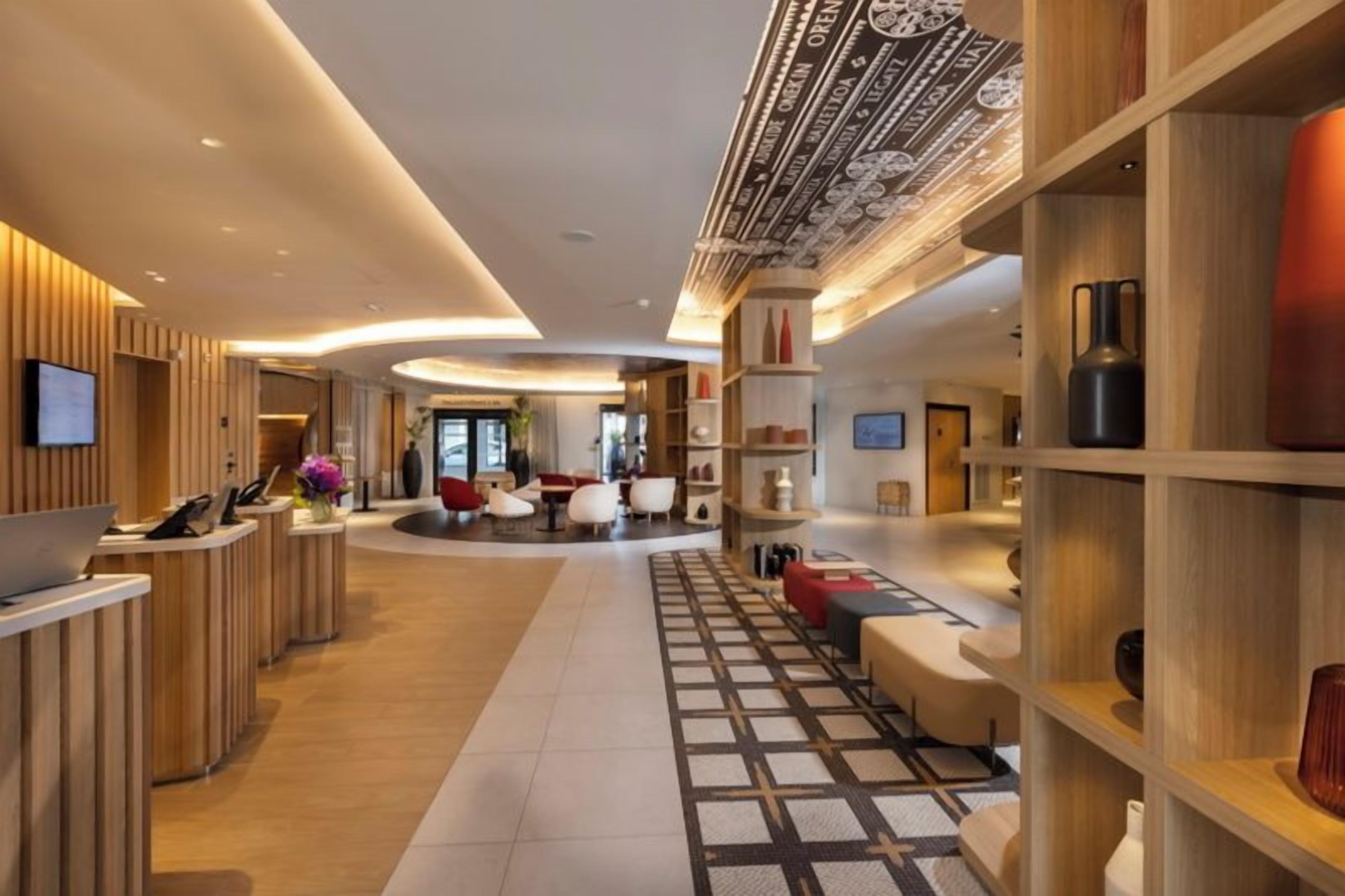 Un moderno vestíbulo de hotel con mostrador de recepción, zona de estar y techo decorativo.