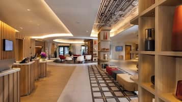 Un moderno vestíbulo de hotel con mostrador de recepción, zona de estar y techo decorativo.