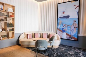 Una sala de estar moderna con un sofá curvo, una mesa de centro redonda y un cuadro grande de un barco en la pared.