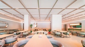 Un restaurante moderno con mesas redondas y cabinas, una zona central de servicio y un techo decorativo.