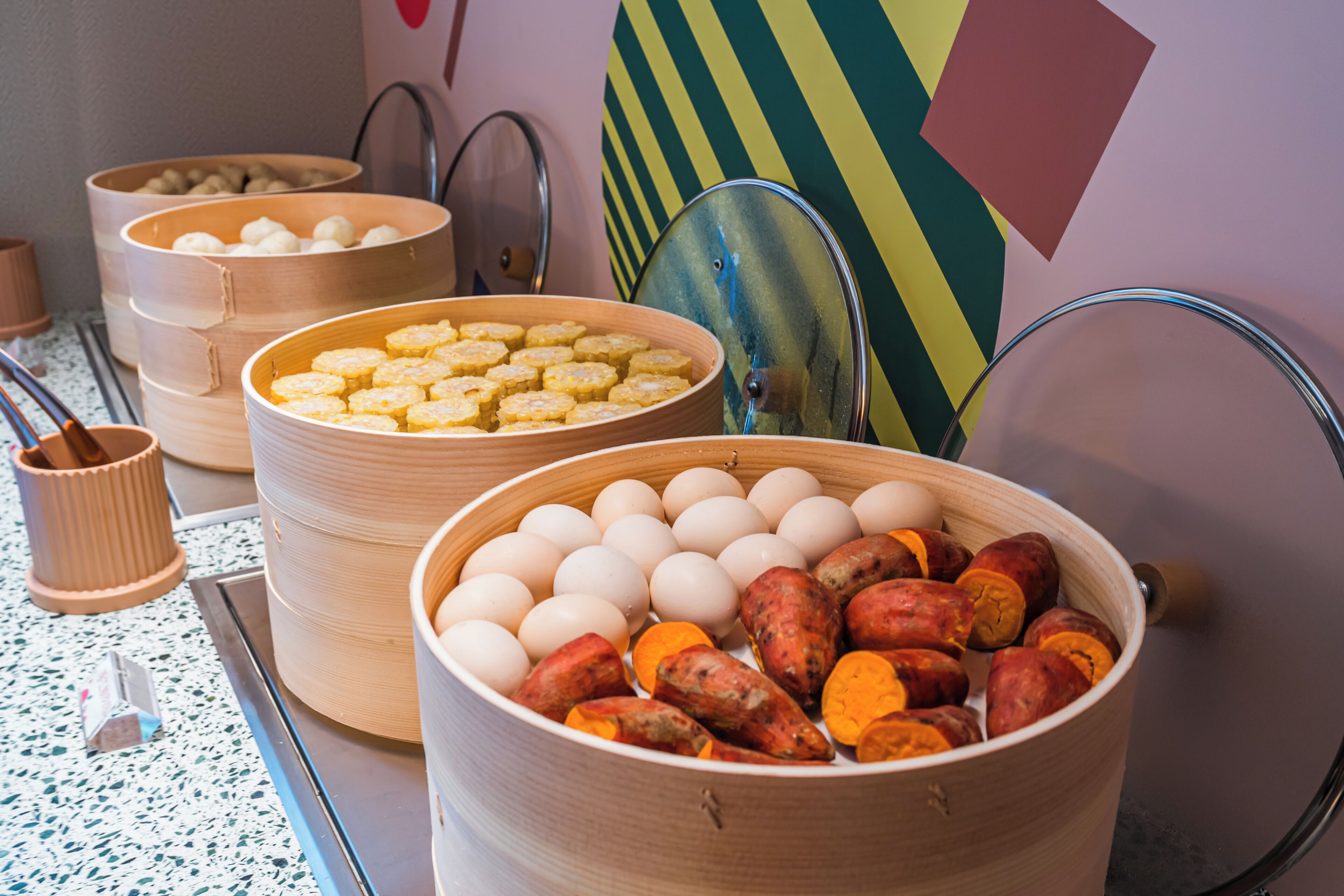 A buffet table with various food items including eggs, sweet potatoes, and biscuits.