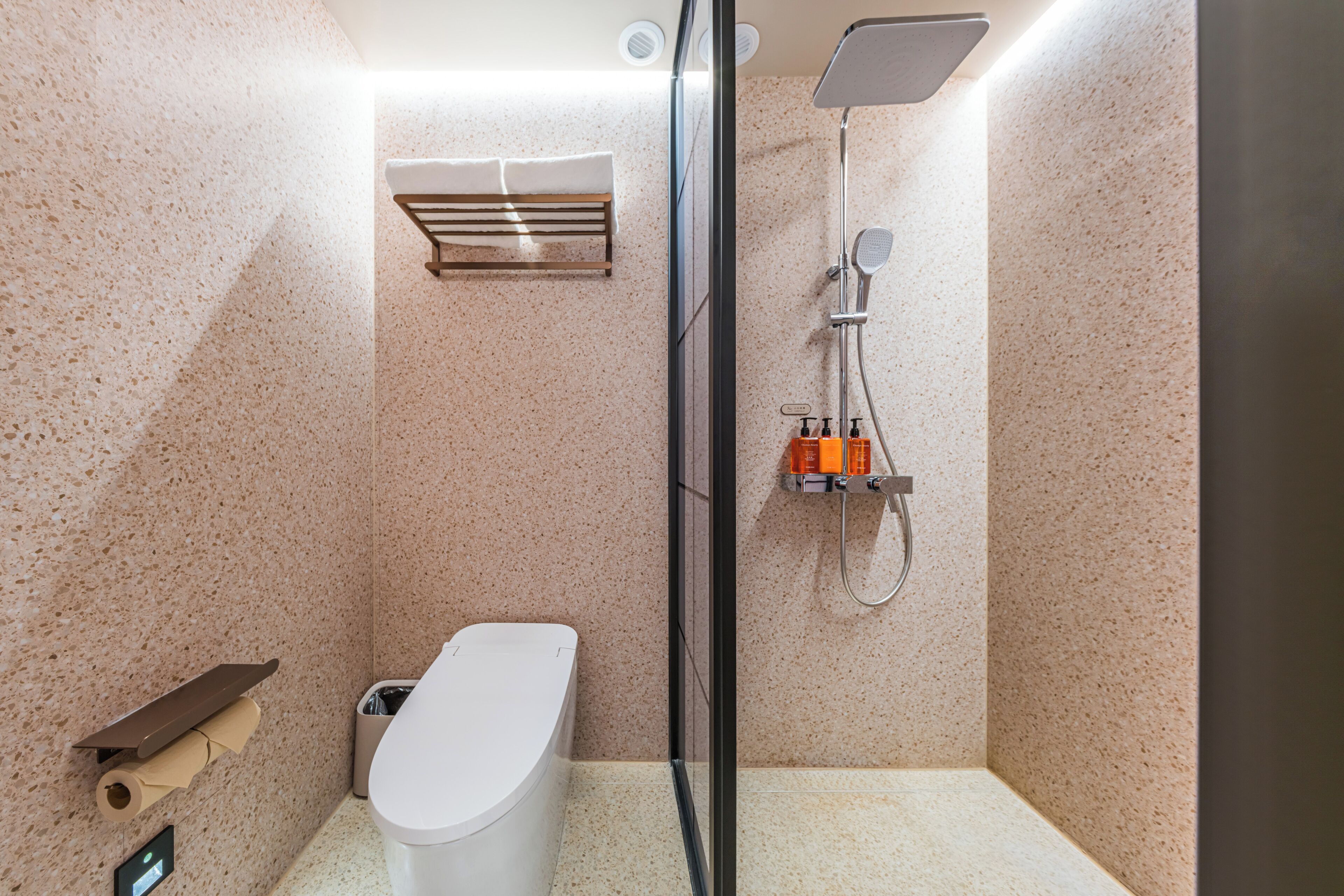 A modern bathroom with a shower, toilet, and towel rack.