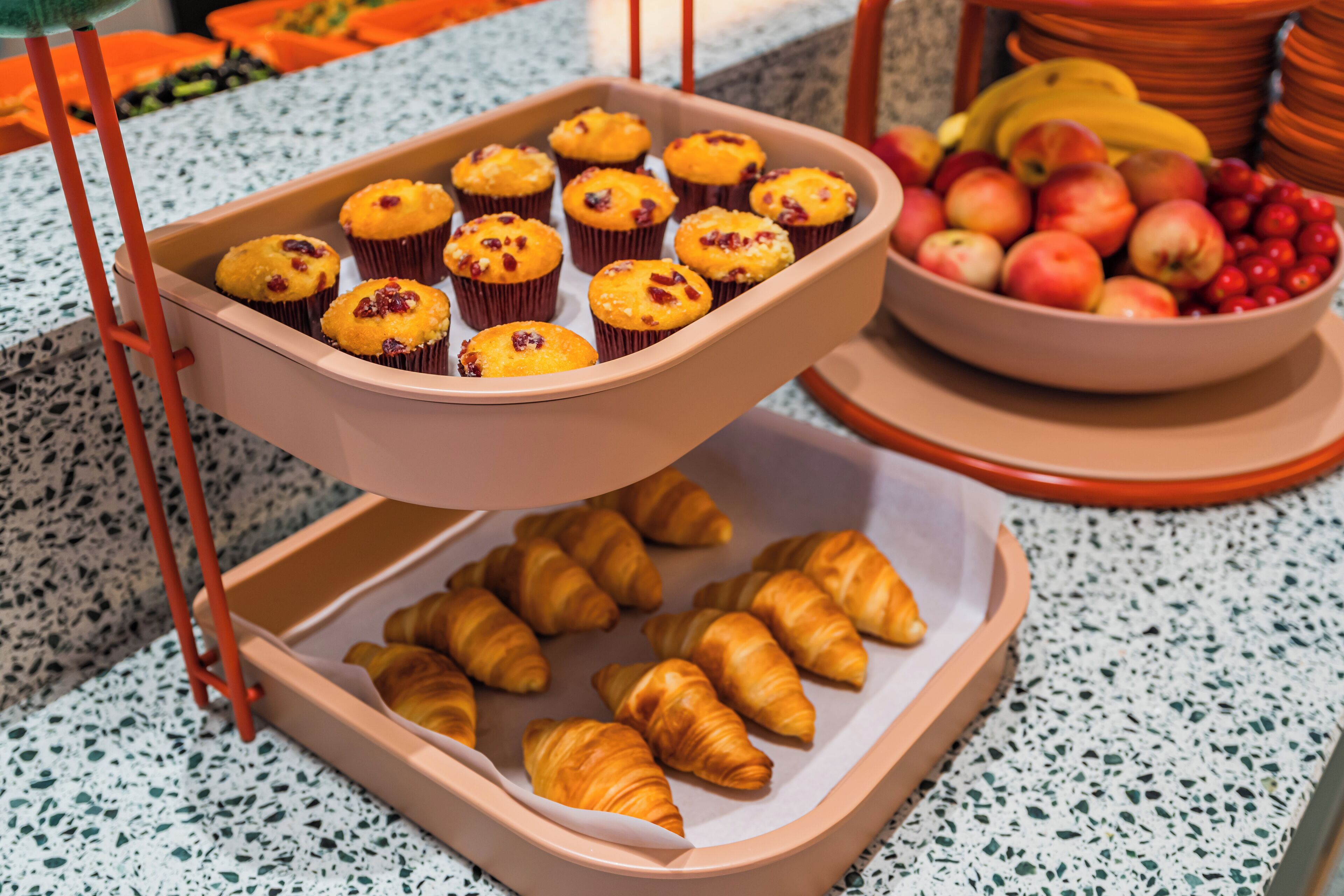 Un plateau rempli de muffins et de croissants est posé sur un comptoir.