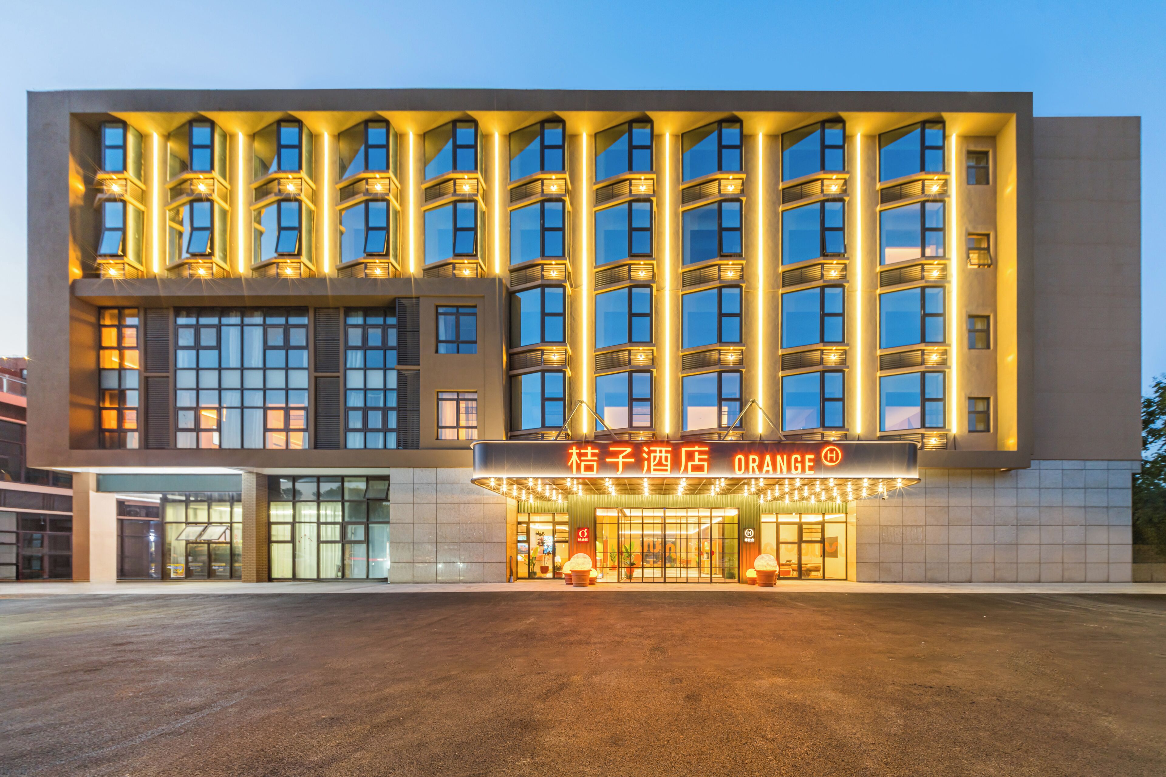 Un hotel con fachada moderna, varios balcones y una entrada destacada con señalización iluminada.