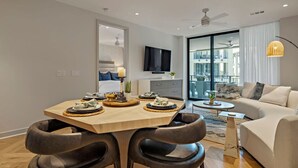 Un salon moderne avec un canapé, une table à manger dressée avec de l’assiette et un téléviseur fixé au mur.