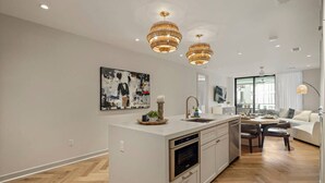 Une cuisine moderne dotée d’un îlot central, de luminaires suspendus et d’un coin repas avec un canapé et une table.