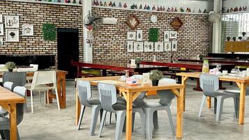 A dining area with brick walls, wooden tables, and plastic chairs.