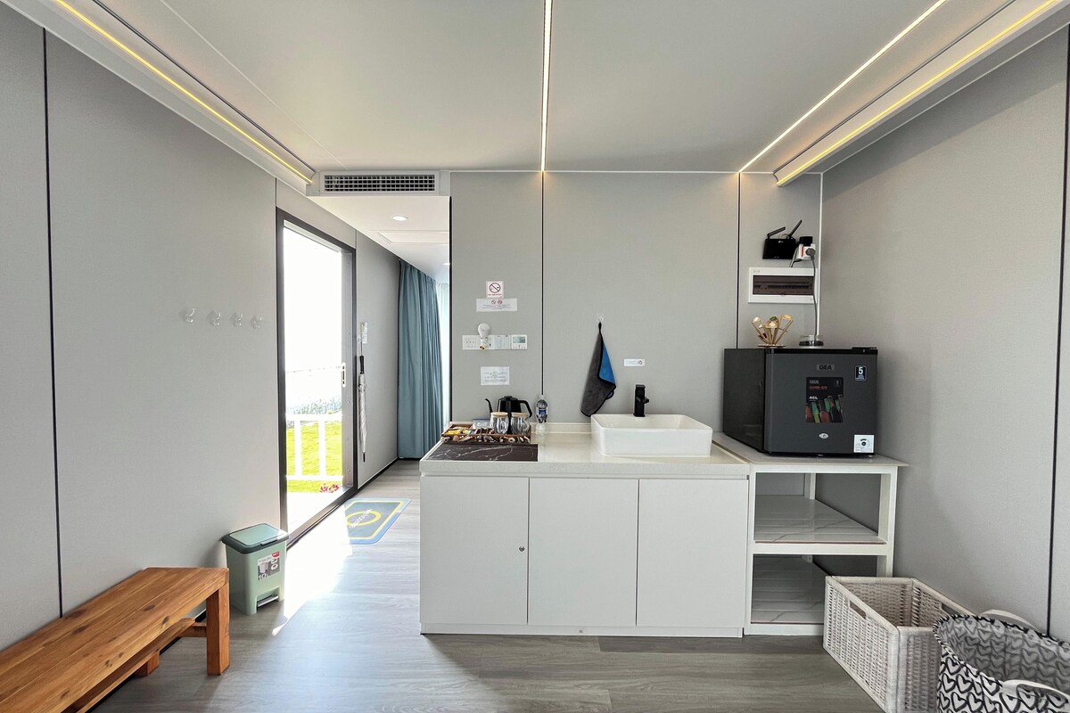 A modern kitchen with a central island, white cabinetry, and a built-in microwave.