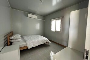 A bedroom with a bed, a desk, a wardrobe, and a window. - Saga Village Hotel & Resort Bintan By Zuzu (Bintan)