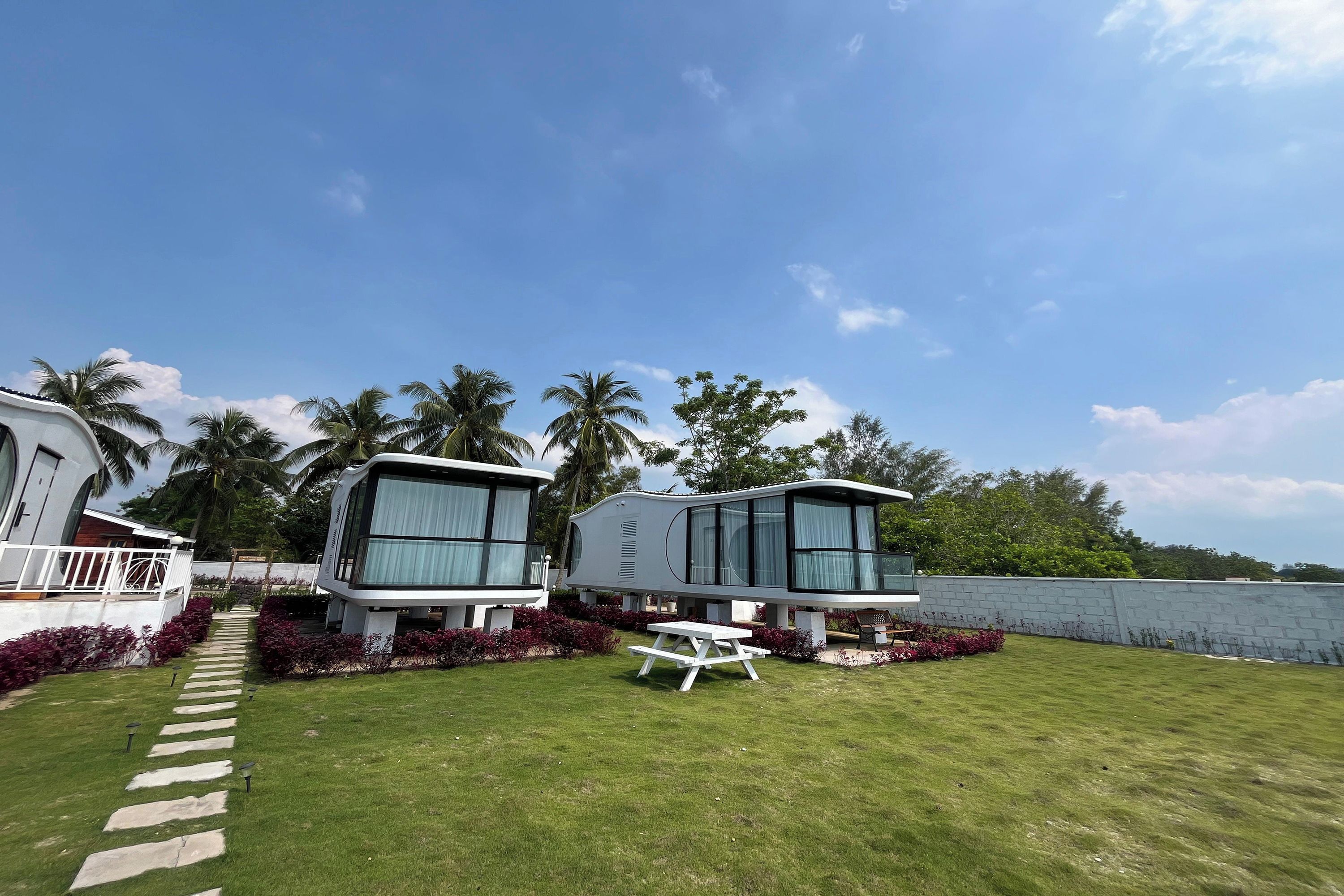 A modern vacation home with a paved pathway leading to a white picnic table.